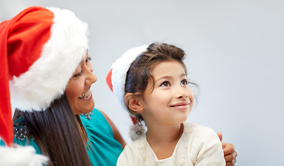 Image showing happy mother and little girl in santa hats at home