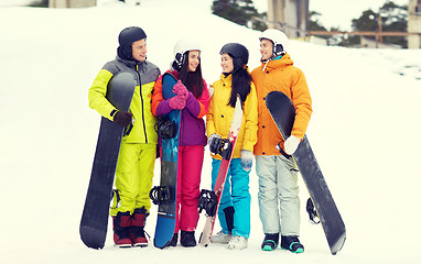 Image showing happy friends in helmets with snowboards talking