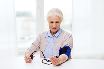 Image showing old woman with tonometer checking blood pressure