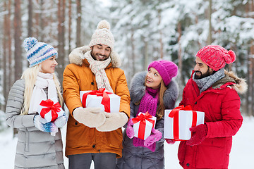 Image showing happy friends with gift boxes in winter forest