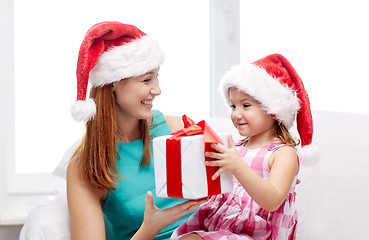 Image showing happy mother and child in santa hats with gift box