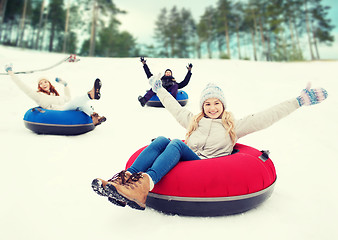 Image showing group of happy friends sliding down on snow tubes