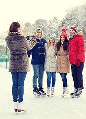 Image showing happy friends with smartphone on ice skating rink