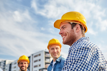 Image showing group of smiling builders in hardhats outdoors