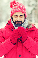 Image showing smiling young man with cup in winter forest