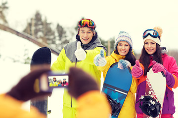 Image showing happy friends with snowboards and smartphone