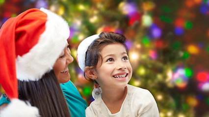 Image showing happy mother and little girl in santa hats at home