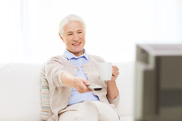 Image showing senior woman watching tv and drinking tea at home