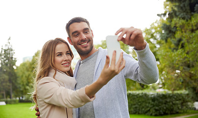 Image showing happy couple with smartphone taking selfie in park