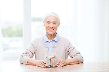 Image showing senior woman with money in glass jar at home