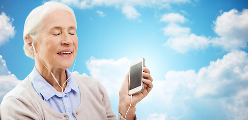 Image showing senior woman with smartphone and earphones at home