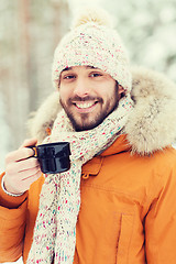 Image showing smiling young man with cup in winter forest