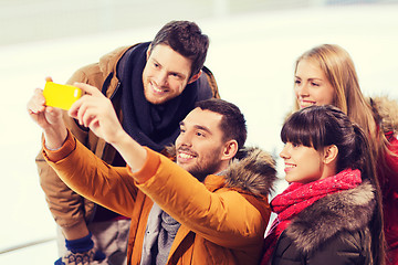 Image showing happy friends with smartphone on skating rink