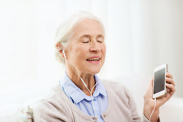 Image showing senior woman with smartphone and earphones at home