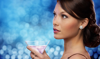 Image showing smiling woman holding cocktail over blue lights