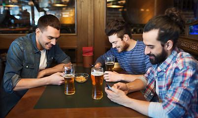 Image showing male friends with smartphones drinking beer at bar