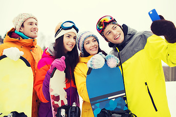 Image showing happy friends with snowboards and smartphone