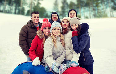 Image showing smiling friends with snow tubes and selfie stick