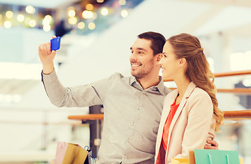 Image showing happy couple with smartphone taking selfie in mall