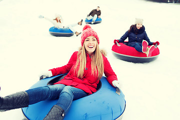 Image showing group of happy friends sliding down on snow tubes