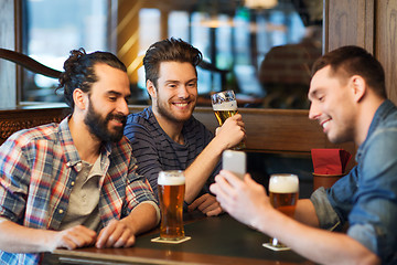 Image showing male friends with smartphone drinking beer at bar