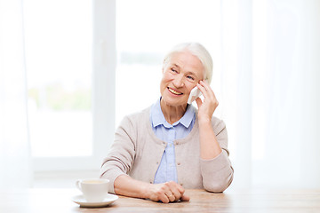 Image showing senior woman with smartphone calling at home