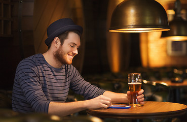 Image showing man with smartphone and beer texting at bar