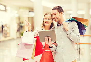 Image showing couple with tablet pc and shopping bags in mall