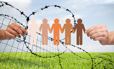 Image showing hands holding people pictogram over barb wire