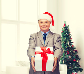 Image showing smiling man in suit and santa helper hat with gift