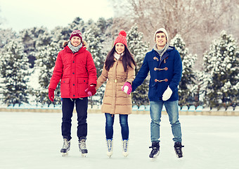 Image showing happy friends ice skating on rink outdoors