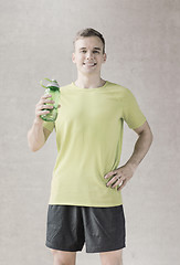 Image showing smiling man with bottle of water in gym