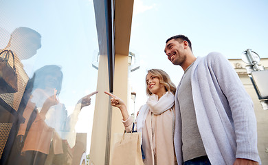 Image showing happy couple with shopping bags at shop window