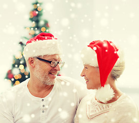 Image showing happy senior couple in santa helper hats at home