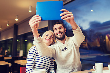Image showing happy couple with tablet pc taking selfie at cafe