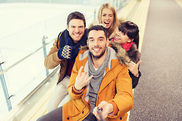 Image showing happy friends taking selfie on skating rink