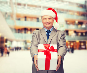 Image showing smiling man in suit and santa helper hat with gift