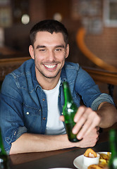 Image showing happy young man drinking beer at bar or pub
