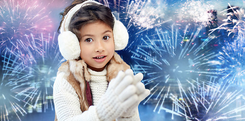 Image showing happy little girl wearing earmuffs over firework