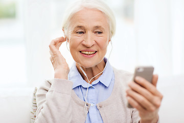 Image showing senior woman with smartphone and earphones at home