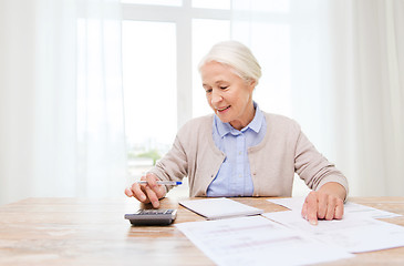 Image showing senior woman with papers and calculator at home