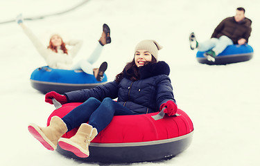 Image showing group of happy friends sliding down on snow tubes