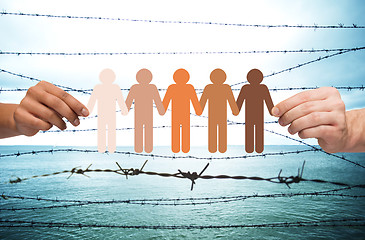 Image showing hands holding people pictogram over barb wire