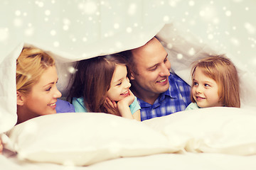 Image showing happy family with two kids under blanket at home