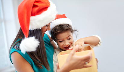 Image showing happy mother and child in santa hats with gift box