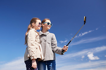 Image showing happy girls with smartphone selfie stick