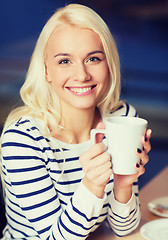 Image showing happy young woman drinking tea or coffee