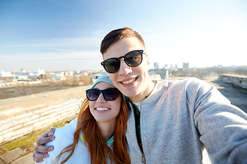 Image showing happy teenage couple taking selfie on city street