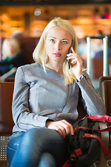 Image showing Female traveler using cell phone while waiting.