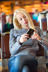 Image showing Female traveler using cell phone while waiting.